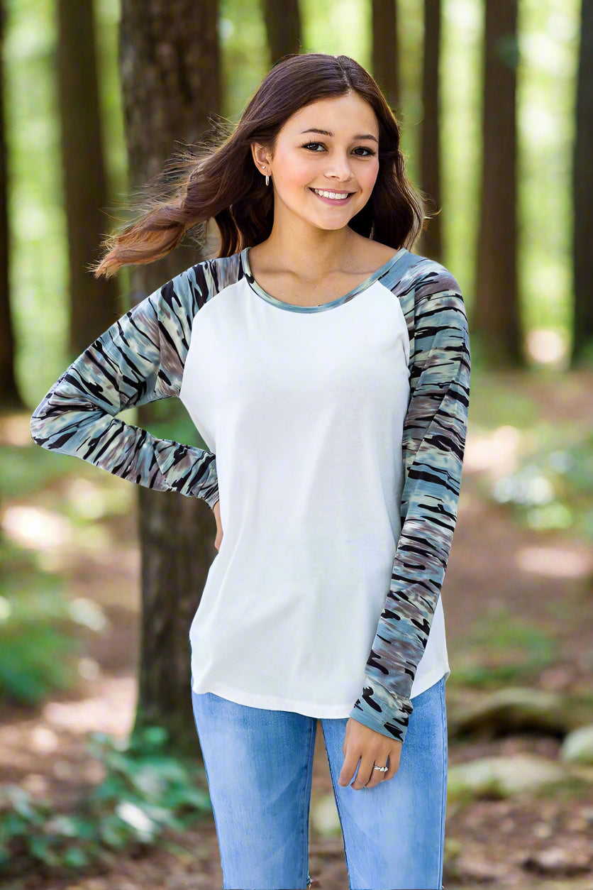 Woman wearing a long-sleeve shirt with a patterned sleeve and white body, standing outdoors.