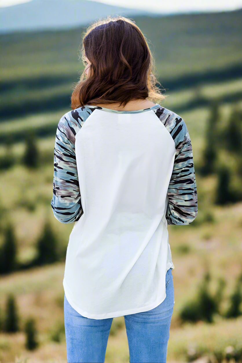 Woman wearing a white and black tie-dye long-sleeve shirt with blue jeans outdoors.